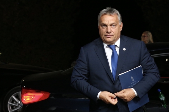 Hongaars premier Viktor Orbán wandelt richting de fotograaf en knoopt zijn jasje dicht.