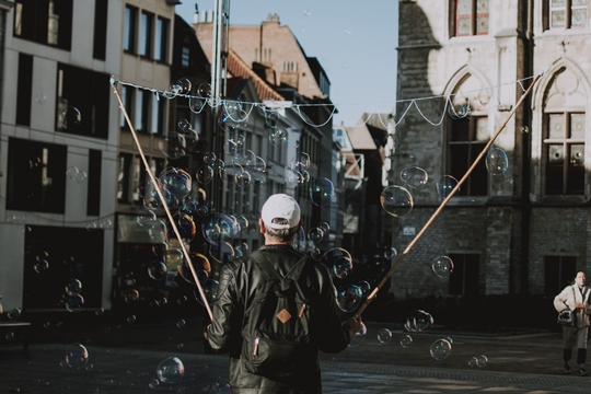 Een man laat zeepbellen vliegen door Gent.