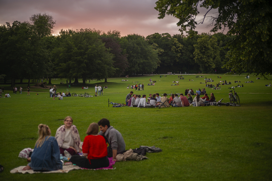 Groepjes mensen zitten bij mooi weer in het gras van Ter Kamerenbos.