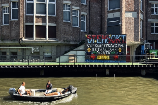 Op een muur aan de Gentse binnenwateren staat een oproep om te stemmen in het woonreferendum op 8 oktober.