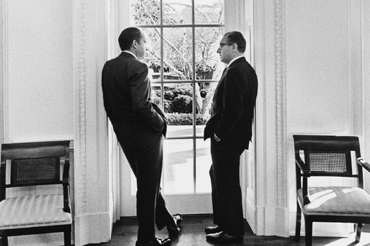 President Richard Nixon en Nationaal Veiligheidsadviseur Henry Kissinger staan bij een raam in het Oval Office van het Witte Huis in 1971.