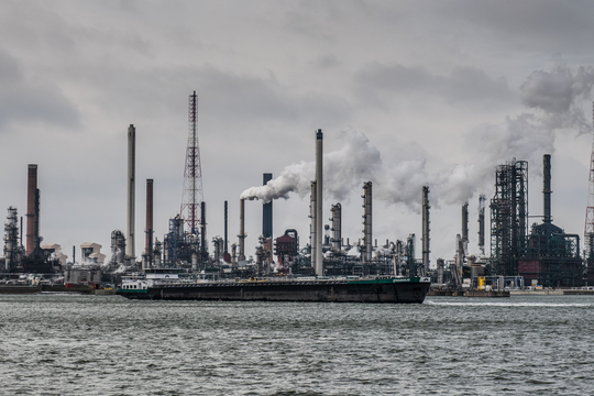 Zicht op een schip in de haven van Antwerpen met op de achtergrond de petrochemische cluster.