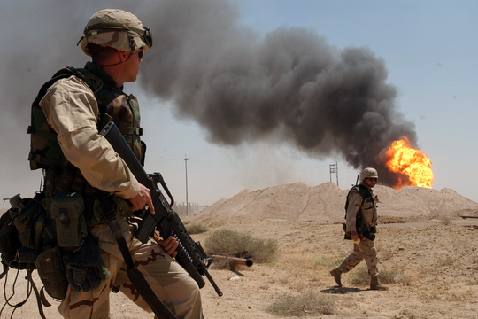 Een Amerikaanse soldaat patrouilleert in 2003 bij een brandend olieveld in Irak (Foto: WikiMedia)