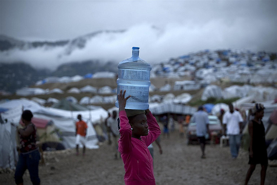 Une jeune fille porte un réservoir d'eau sur sa tête dans campement, Port-au-Prince (Photo: Unicef Canada/ Juillet 2010/ Flickr-CC)